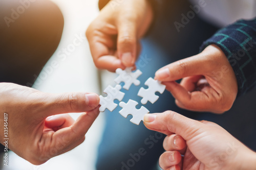 Wallpaper Mural Closeup image of a group of people holding and putting a piece of white jigsaw puzzle together Torontodigital.ca
