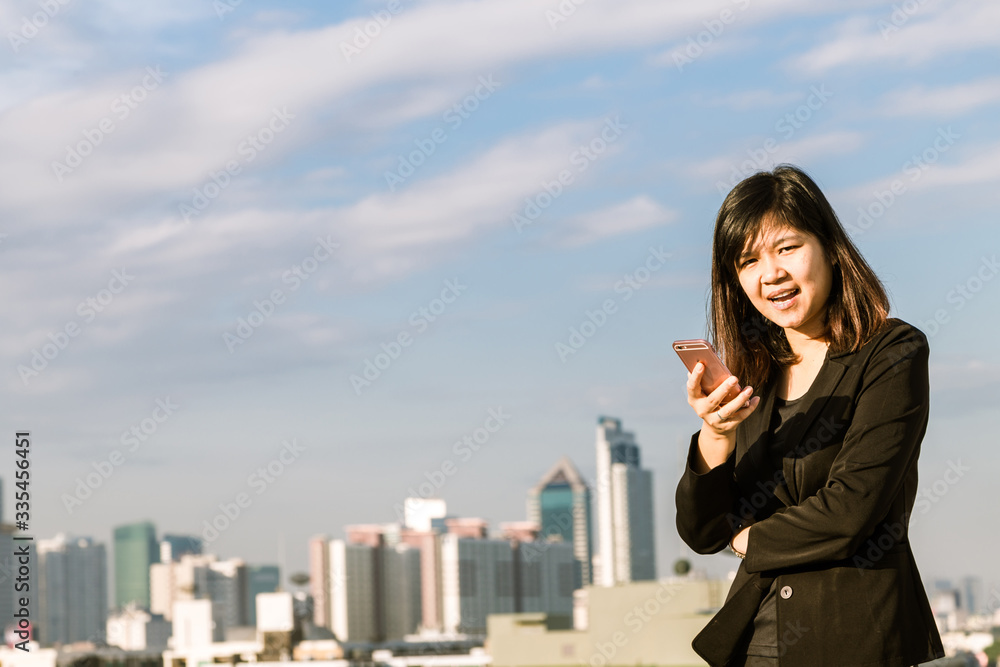 Business asian women wear black smart suit with smartphone on top of building Business asian women wear black smart suit with smartphone on top of building