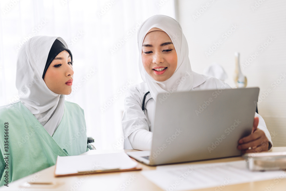 Muslim asian female doctor consulting and check up information on laptop computer with muslim woman in hospital.woman has sick.healthcare and medicine Muslim asian female doctor consulting and check up information on laptop computer with muslim woman in hospital.woman has sick.healthcare and medicine