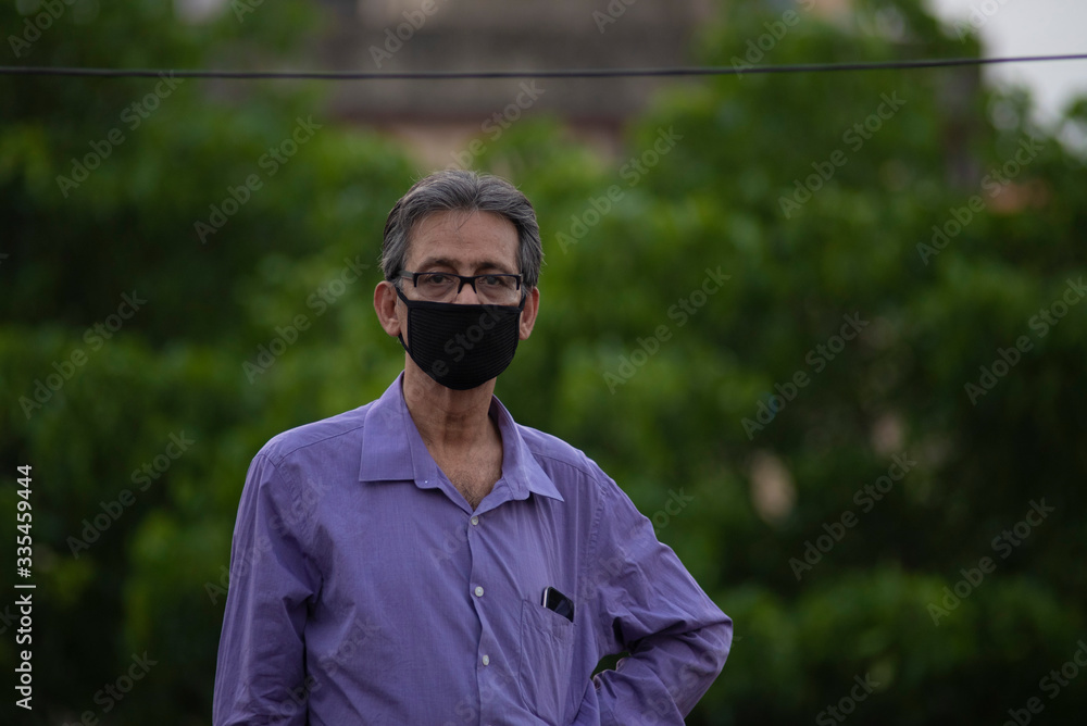 Portrait of an Indian old man with corona preventive mask on a rooftop in home isolation.Indian lifestyle, disease and home quarantine. Portrait of an Indian old man with corona preventive mask on a rooftop in home isolation.Indian lifestyle, disease and home quarantine.