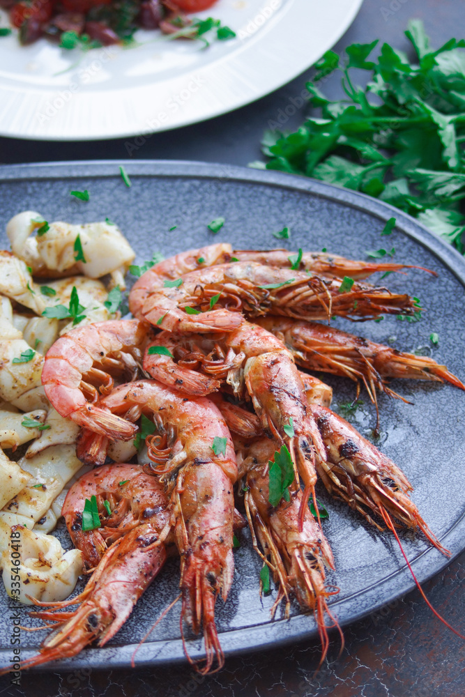Plate with seafood, King prawns and squid, Fish menu in the restaurant, Dark background Plate with seafood, King prawns and squid, Fish menu in the restaurant, Dark background