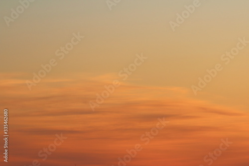 Sun below the horizon and clouds in the fiery dramatic orange sky at sunset or dawn backlit by the sun. Place for text and design. © Stanislav