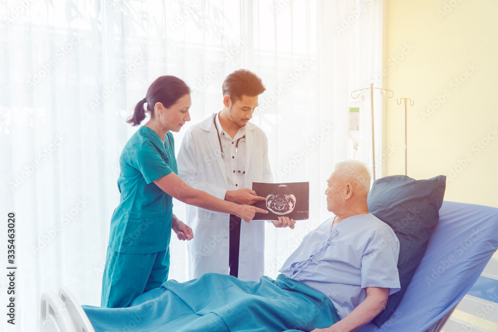 Obraz premium Asian male Patient On Ward. Strong Asian Man Go to Visit Doctor For Check His Health Of The Year. Caregiver In elderly home care giving help on the bed. Hospital and Medicine and health care Concept