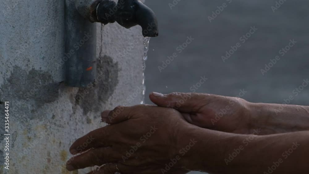A person washing hands in tap water using sanitizer to prevent corona virus infection. Indian lifestyle, covid 19, pandemic 