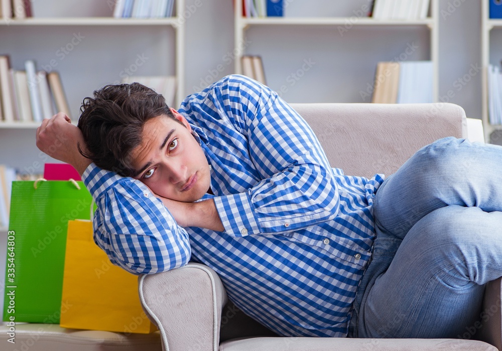 Obraz premium Young man after excessive shopping at home