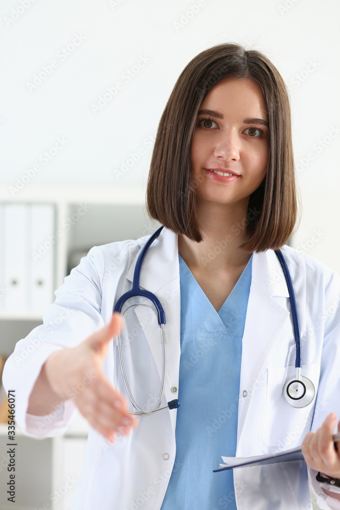 Female medicine doctor hold pad and give arm to shake in office closeup. Friend welcome, introduction or thanks gesture, test work, examine patient, congratulation, help exam, teamwork deal concept Female medicine doctor hold pad and give arm to shake in office closeup. Friend welcome, introduction or thanks gesture, test work, examine patient, congratulation, help exam, teamwork deal concept