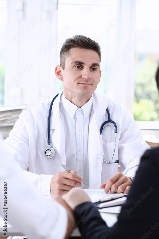 Male family doctor listen carefully young couple in office portrait. Motherhood and child delivery, new life or abortion, therapeutist reception service, physical, hospital and clinic concept
