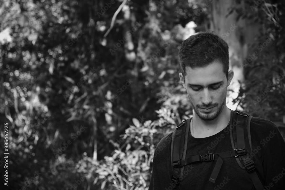 a model man dressed as a hiker or walker with a technical bag over a background of trees and branches of a forest a model man dressed as a hiker or walker with a technical bag over a background of trees and branches of a forest