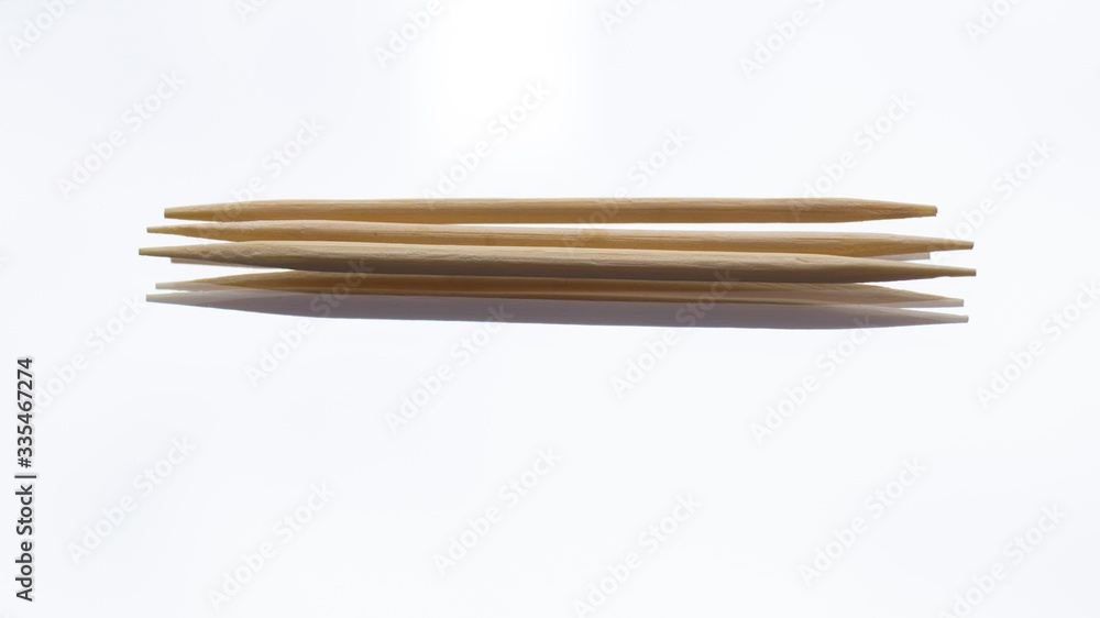 Three wooden sharp toothpicks on a white mirror background. Oral hygiene. Brushing teeth after eating. Three wooden sharp toothpicks on a white mirror background. Oral hygiene. Brushing teeth after eating.