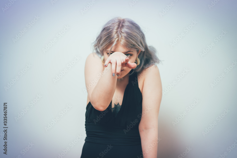 studio portrait of a beautiful girl pointing to the camera