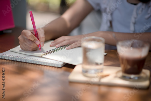 A woman writes with a pencil on a notebook at home. Women who work outdoors at home