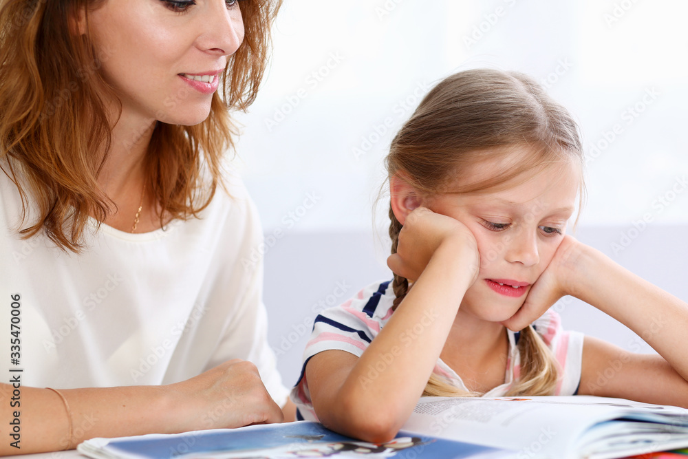 Blond little reading together with mom. Beautiful female young reader, minor baby-sitter, fairy tale joy, story, juvenile development, parent lifestyle, youth concept Blond little reading together with mom. Beautiful female young reader, minor baby-sitter, fairy tale joy, story, juvenile development, parent lifestyle, youth concept