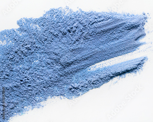 A top view of a loose blue cosmetic or food powder pigment on a white background. Colorful texture. Copy space. Close-up. Blue matcha
