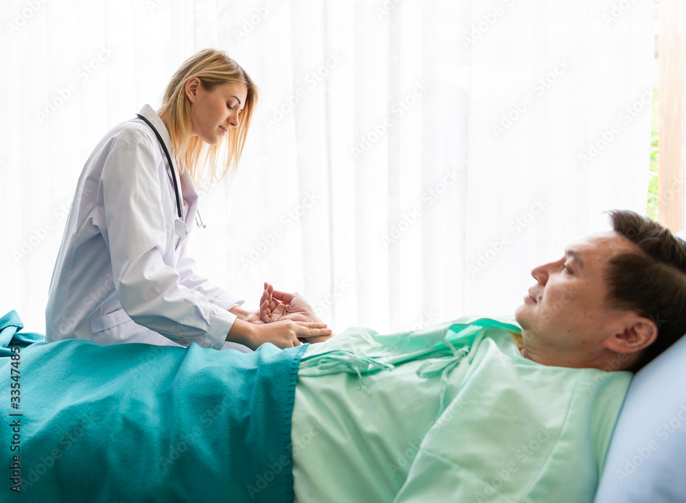 Nurse in white uniform take care and consoling elderly patient lying on the bed in ward at hospital Nurse in white uniform take care and consoling elderly patient lying on the bed in ward at hospital