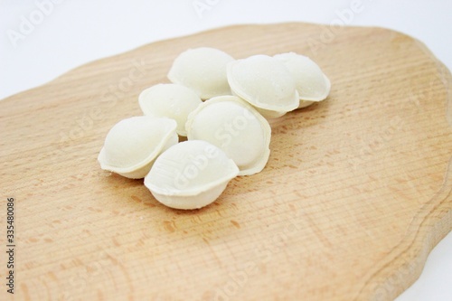 Frozen raw dumplings located on a wooden board