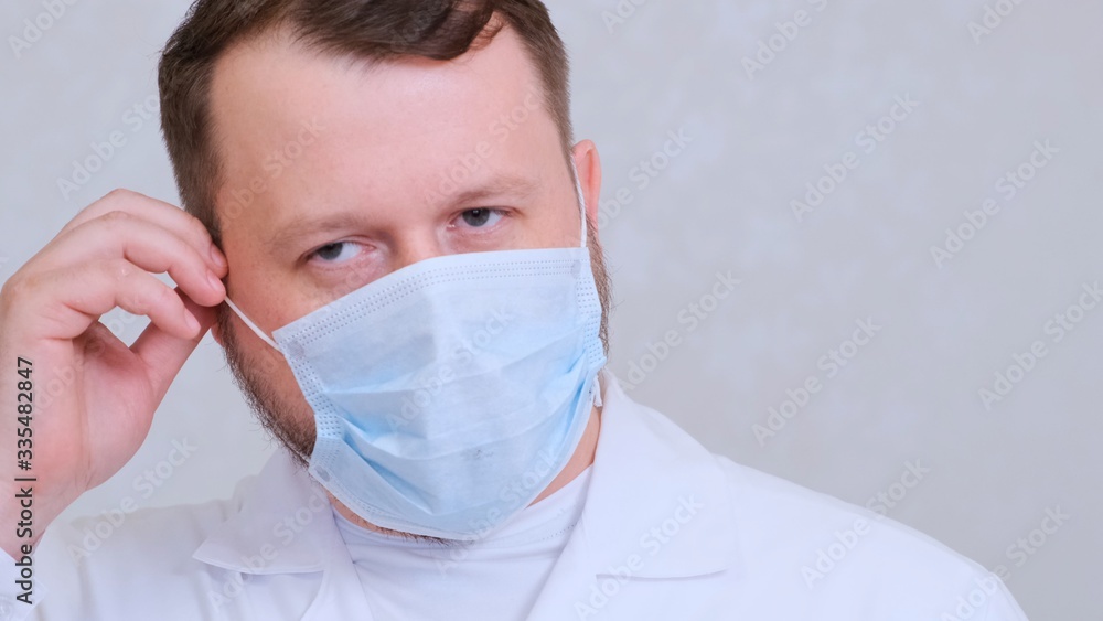 bearded male doctor takes off his protective mask with a sad look. This is the end. Hygiene concept. prevent the spread of germs and bacteria and avoid infection with the crown virus