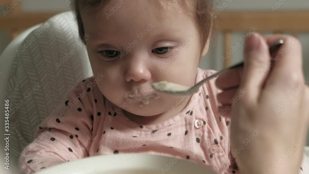Mom feeds a little girl in a highchair. Mom feeds a little girl in a highchair.
