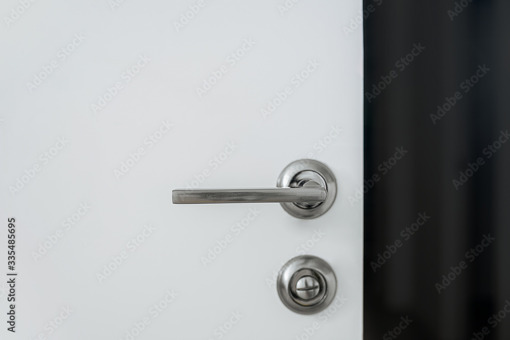 Metal handle with a lock on a white door Metal handle with a lock on a white door
