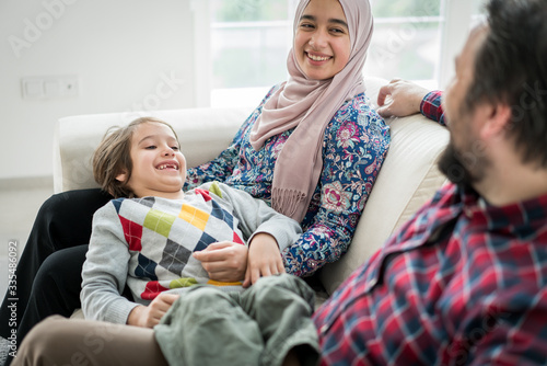 Sticker Middle Eastern family sitting on sofa in living roome at home