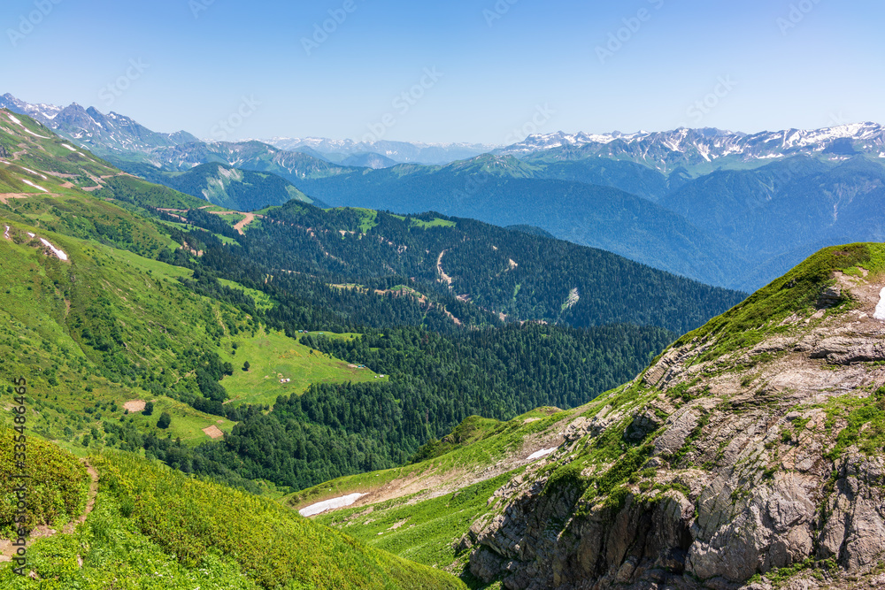 View over the Green Valley, surrounded by high mountains with snow on a clear summer day.