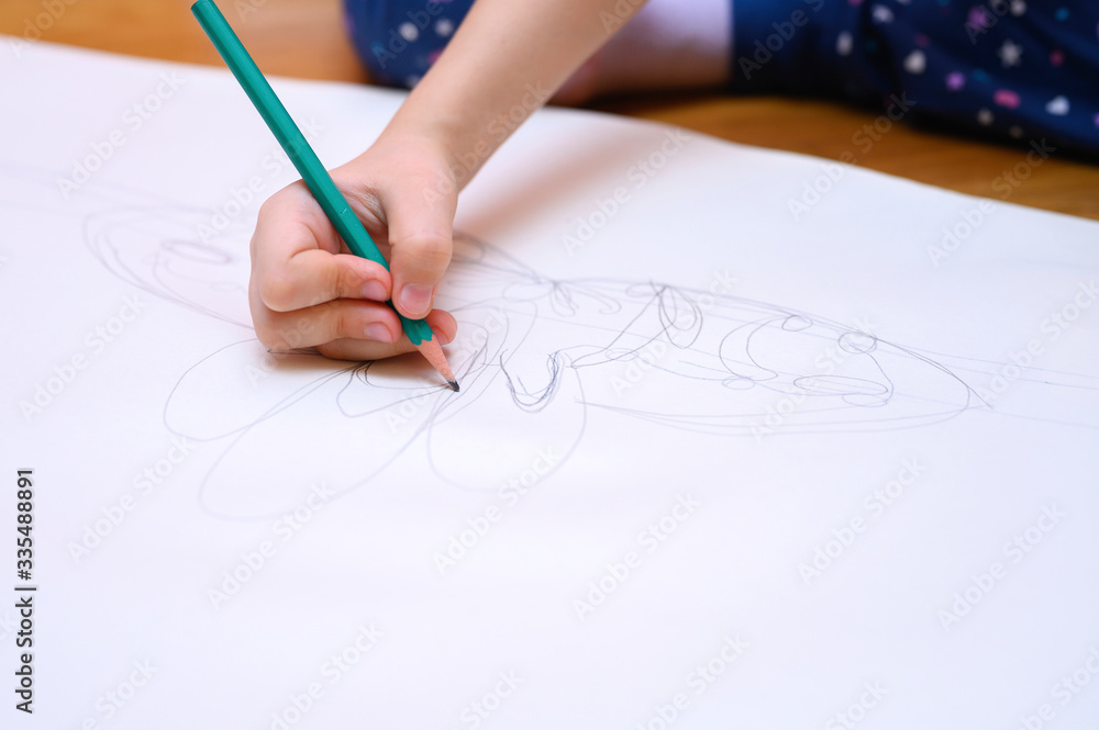 kids hobby. a little six year old child girl draws with a pencil on paper sitting on the floor at home. the concept of home exercises during the coronavirus covid-19 quarantine kids hobby. a little six year old child girl draws with a pencil on paper sitting on the floor at home. the concept of home exercises during the coronavirus covid-19 quarantine