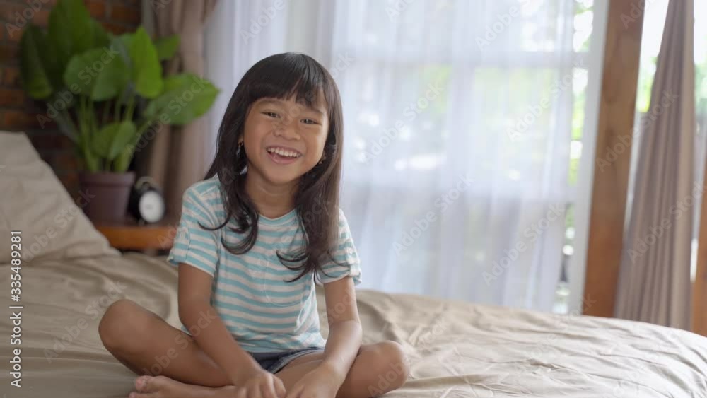 happy excited asian young girl kid sitting on the bed happy excited asian young girl kid sitting on the bed