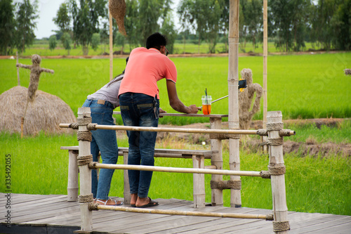 Thai people boyfriend and girlfriend lover travel visit walk on wooden bridge in rice field for take photo of coffee shop at countryside in Ayutthaya, Thailand