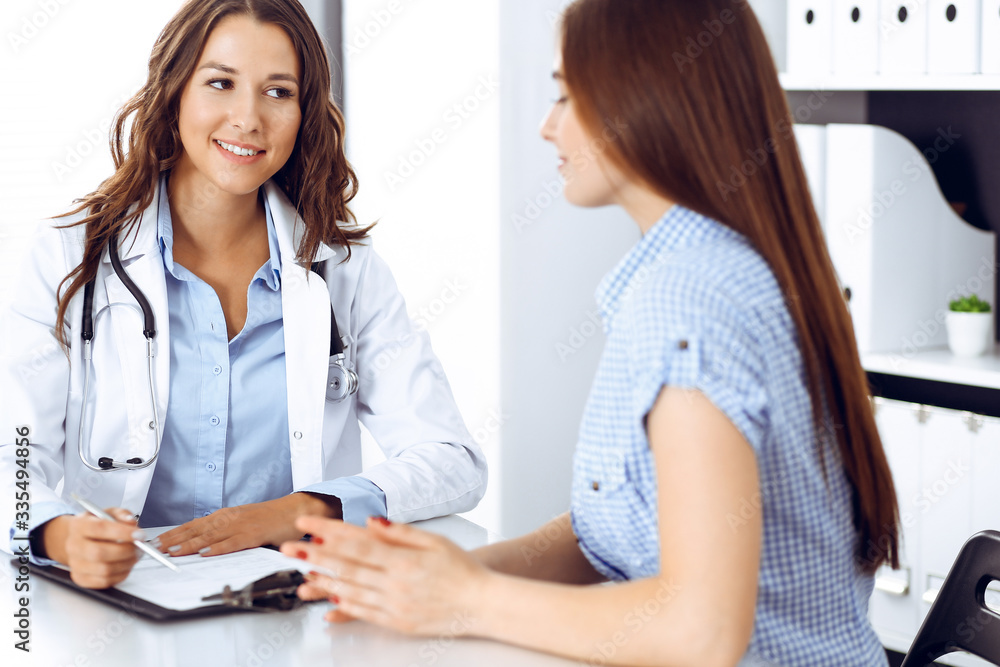 Doctor and patient talking while sitting at the desk. The physician discussing healthy lifestyle. Health care, medicine and patient service concept Doctor and patient talking while sitting at the desk. The physician discussing healthy lifestyle. Health care, medicine and patient service concept