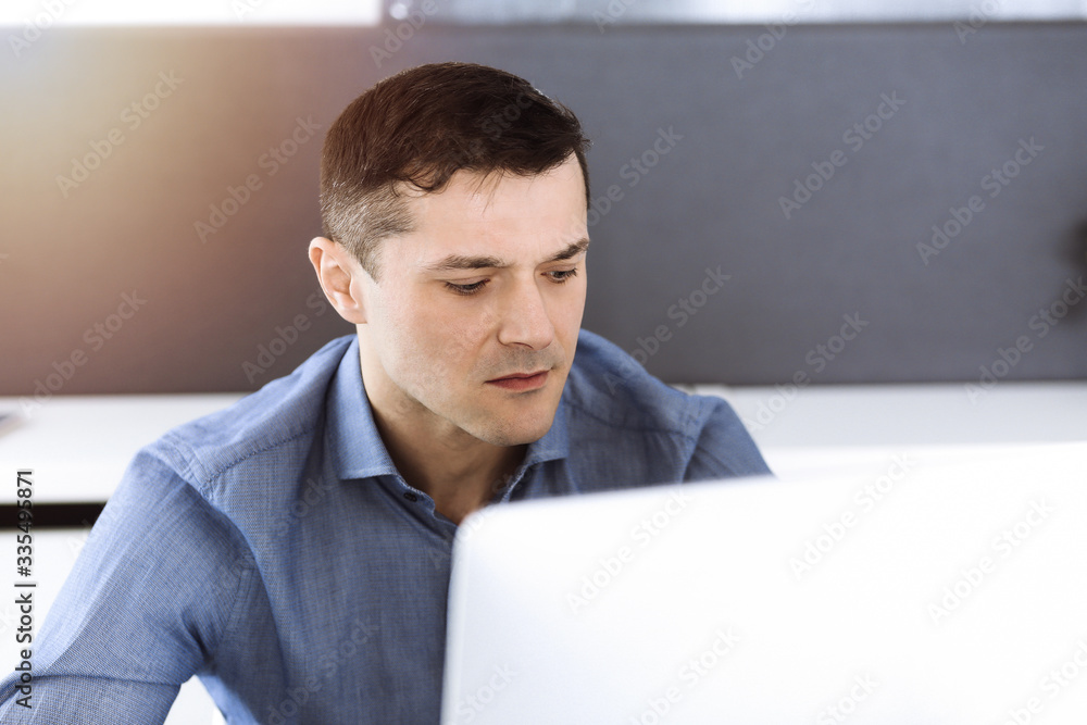 Businessman working with computer in modern sunny office. Headshot of male entrepreneur or company director at workplace. Business concept Businessman working with computer in modern sunny office. Headshot of male entrepreneur or company director at workplace. Business concept
