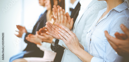 Business people clapping and applause at meeting or conference, close-up of hands. Group of unknown businessmen and women in modern white office. Success teamwork or corporate coaching concept