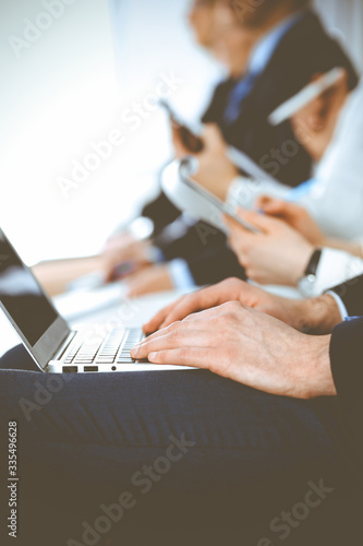 Business people working at meeting or conference, close-up of hands. Group of unknown businessmen and women in modern white office. Teamwork or coaching concept