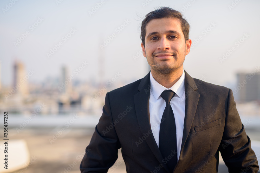 Young Persian businessman in suit against view of the city Young Persian businessman in suit against view of the city
