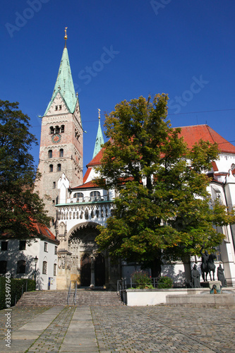 The great catholic Cathedral in Augsburg, Swabia, Bavaria, Germany in bright sunshine, blue sky and surrounded by trees.