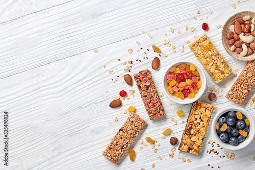 Energy healthy snack. Cereal granola bar with nuts and dry fruit berries. Fitness diet food. Protein muesli bars isolated on white wood. Sport oatmeal bar, top view