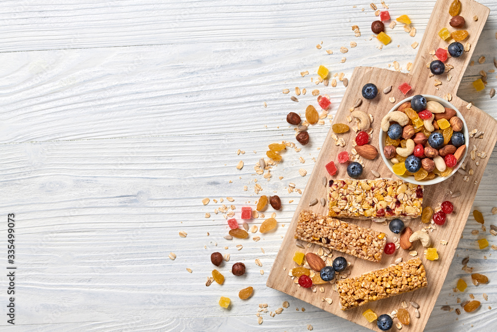 Energy healthy snack. Cereal granola bar with nuts and dry fruit berries. Fitness diet food. Protein muesli bars isolated on white wood. Sport oatmeal bar, top view