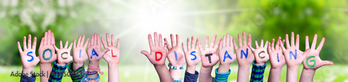 Children Hands Building Colorful English Word Social Distancing. Sunny Green Grass Meadow As Background photo