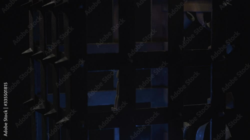 A wooden man is suspended in a rusty metal cage. A wooden man is suspended in a rusty metal cage.