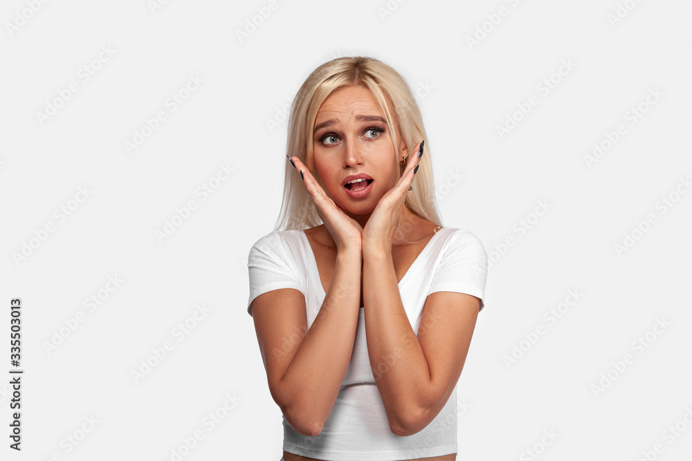 Young blonde woman wearing casual t-shirt standing over isolated white background surprised and shocked, excited and raising hands. Portrait of girl with perfect face and skin. Mockup. Young blonde woman wearing casual t-shirt standing over isolated white background surprised and shocked, excited and raising hands. Portrait of girl with perfect face and skin. Mockup.