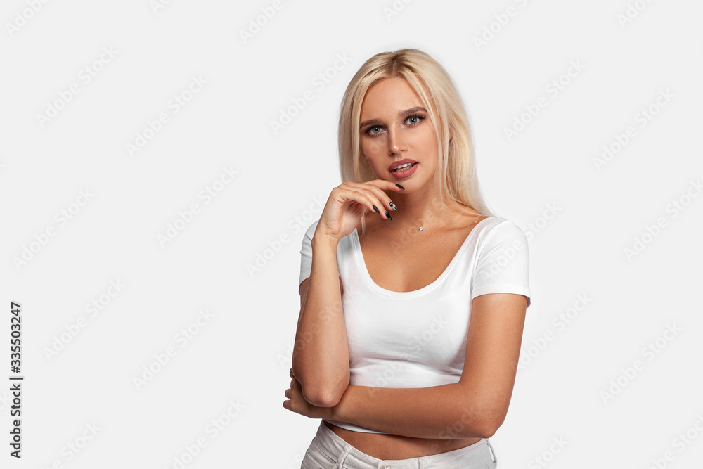 Thinking young european blonde woman isolated on white background. Portrait of girl in white t-shirt with perfect face and skin. Mockup. Thinking young european blonde woman isolated on white background. Portrait of girl in white t-shirt with perfect face and skin. Mockup.
