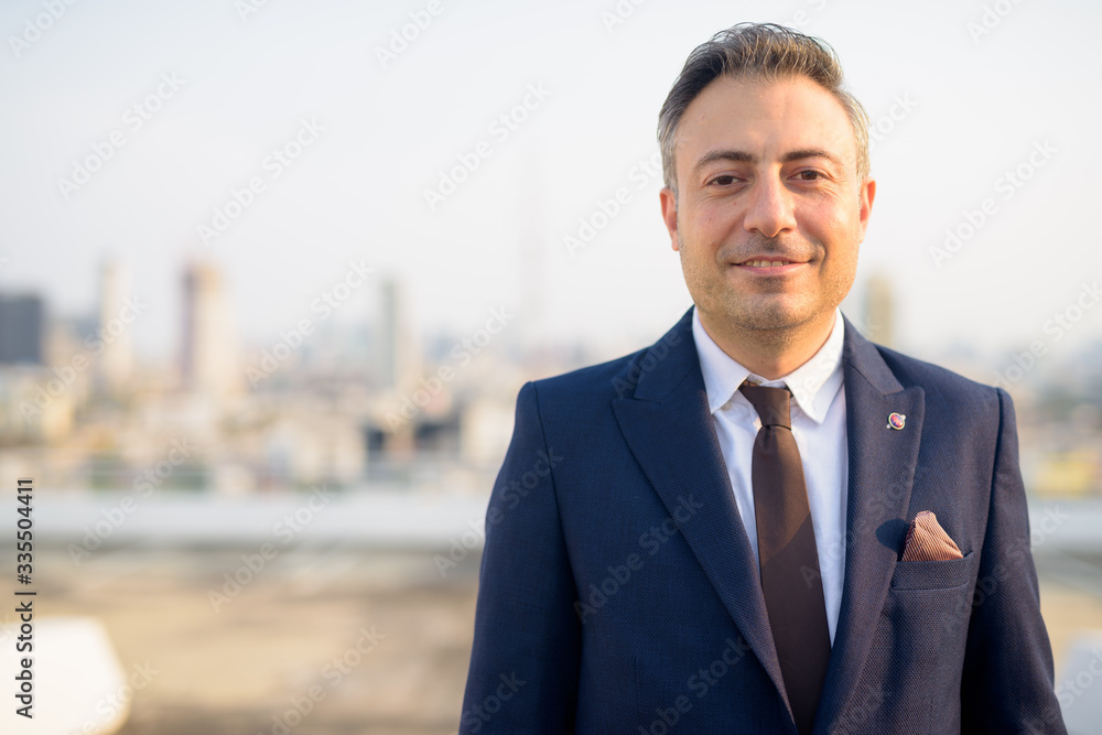 Face of happy mature businessman smiling against view of the city Face of happy mature businessman smiling against view of the city