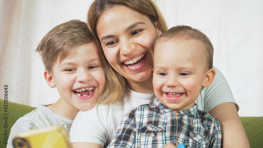 Beautiful mom with sons having a facetime video call. Happy family taking selfies and video chatting at home. Mother's day, unity, connection concept. Beautiful mom with sons having a facetime video call. Happy family taking selfies and video chatting at home. Mother's day, unity, connection concept.