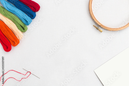Embroidery hoop, needle and different color of thread for sewing lying on a white background. Set for needlework top view