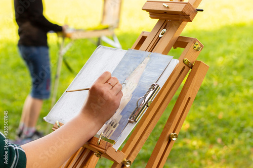 Valokuva artist painting on open air, wooden easel sketchbook with unfinished painting close-up