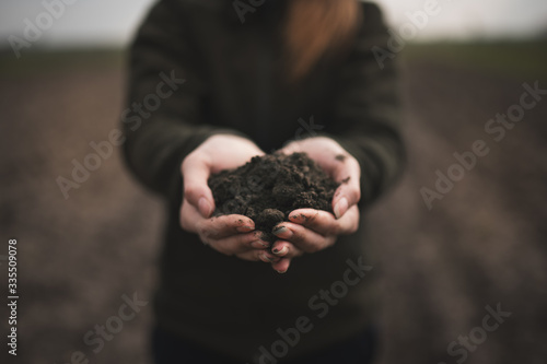 Photos Female hands pouring a black soil in the field