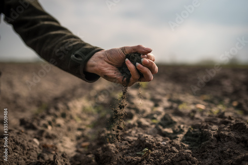 Female hands pouring a black soil in the field. Female agronomist testing a quality of soil. Concept of agriculture.
