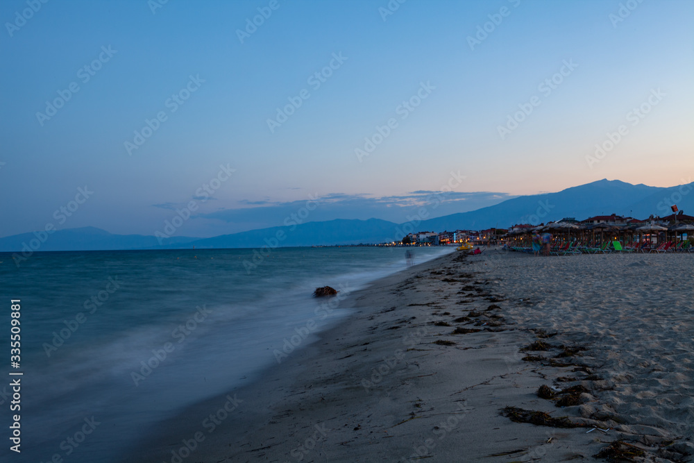 Sea coast and beach at night. Houses along the shore. Pieria, Greece.