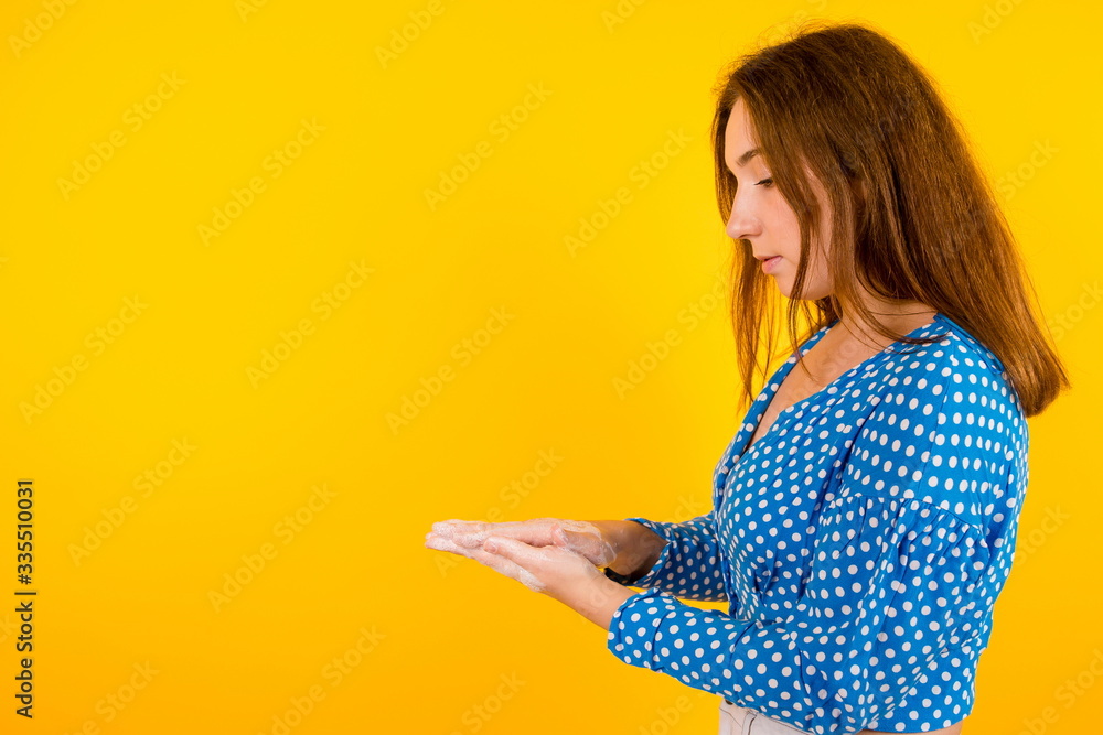 Beautiful girl on a yellow background. Washes his hands with soap to protect himself from viruses Beautiful girl on a yellow background. Washes his hands with soap to protect himself from viruses