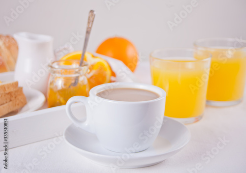 Cup of coffee or tea, bread toast with orange jam, glasses of orange juice on the white background. Breakfast concept.