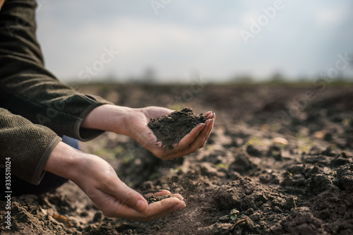 Photos Female hands pouring a black soil in the field