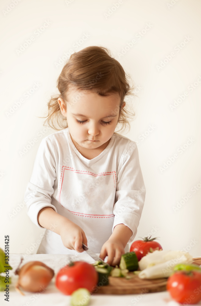 Cute curly girl prepares vegetables for salad in home kitchen. Healthy eating. Cute curly girl prepares vegetables for salad in home kitchen. Healthy eating.